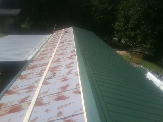 Old rusted panels beside newly installed green metal roofing — Wind Damage Roof Repair by Roofing Brothers in Front Royal