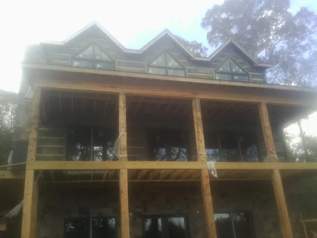 Dormers and porch framing on a large log home under construction — Roof Coating work by our crew in Front Royal