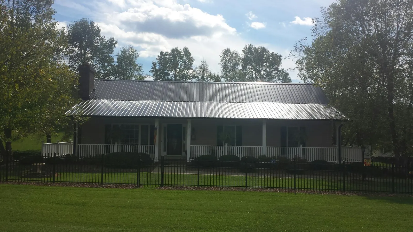 Gray metal roof on a brick ranch with a full width front porch — Gutter Guard Installation work by our crew in Front Royal