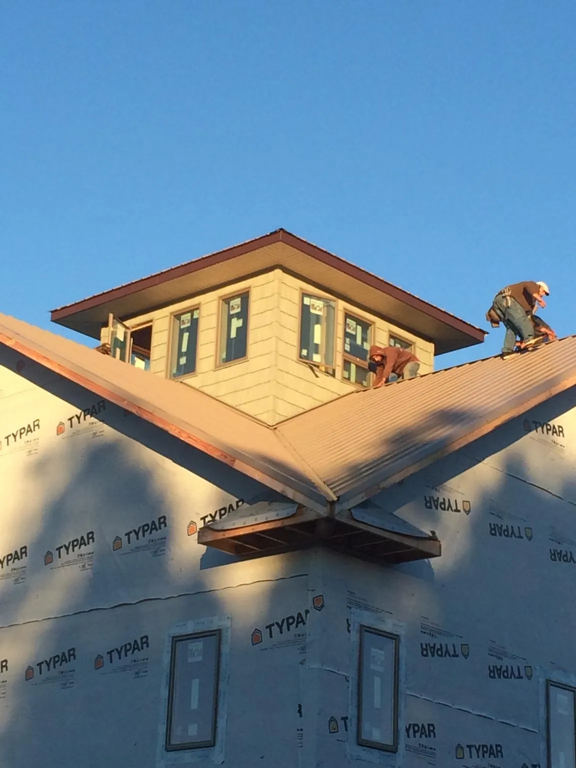 Roofers working around a rooftop cupola on a new metal roof at sunset — Roof Waterproofing in Front Royal by Roofing Brothers